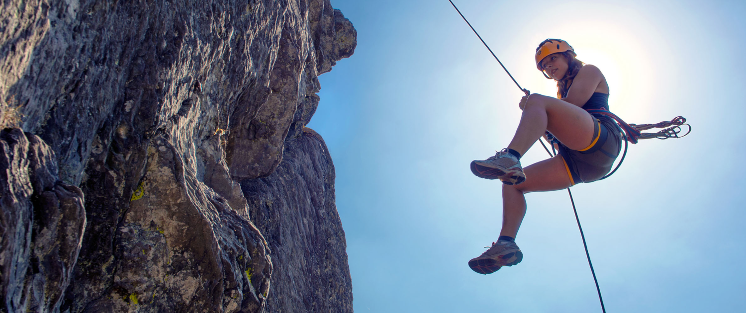 Young, tough, woman, abseiling from a steep rock, just in front